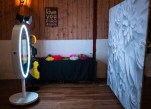 a magic mirror booth on the left and flower-themed photography backdrop on the right 