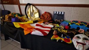 A table full of magic mirror booth props including a mask, cowboy and clown hats, an oversized glasses