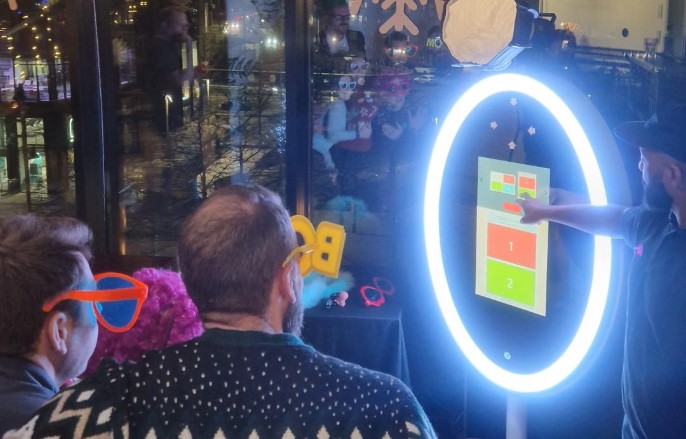 magic mirror booth at a Manchester corporate christmas party with people taking a picture wearing props