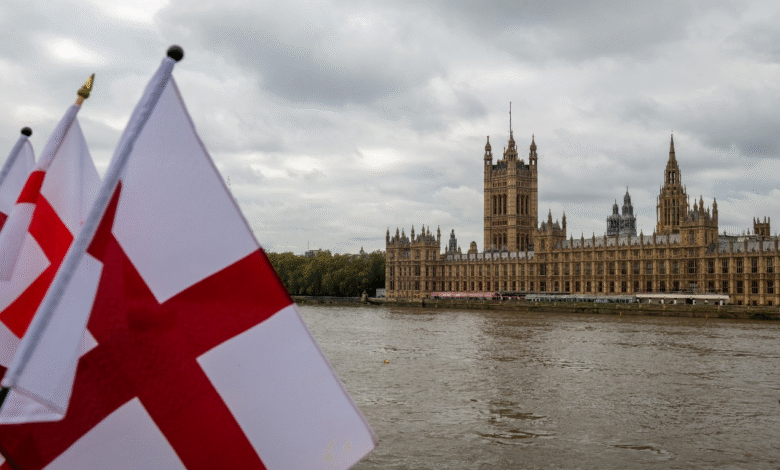 The Houses of Parliament by the Thames river on a grey cloudy day symbolizing the controversy over local councils removing St George’s Flags.